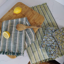 Load image into Gallery viewer, A blue striped kitchen towel over a cutting board and a green striped towel under a oven mitt and pot holder. 