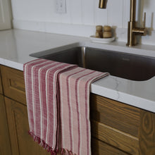 Load image into Gallery viewer, Burgundy and pink striped towels draped over sink. 