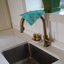 Load image into Gallery viewer, Kitchen sink with gold faucet and green dishcloth, white cabinets in the background