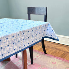 Load image into Gallery viewer, Tablecloth with blue and white b;ock print squiggle pattern on a wooden table against a gray wall.