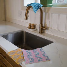 Load image into Gallery viewer, Kitchen sink with gold faucet, colorful dishcloths, and soap on a marble countertop.